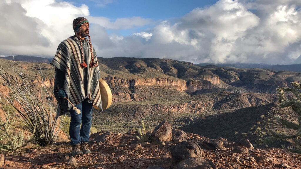 A figure in a
striped poncho standing at the edge of a canyon, looking out.